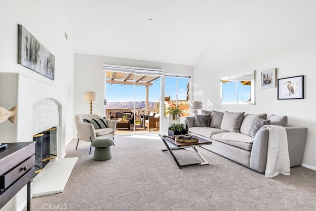 carpeted living area featuring a glass covered fireplace, high vaulted ceiling, and baseboards