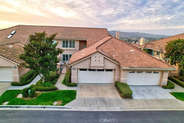 view of front facade with a gate, driveway, stucco siding, a garage, and a tile roof