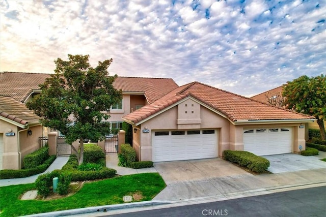 view of front of home with concrete driveway, a gate, an attached garage, and stucco siding