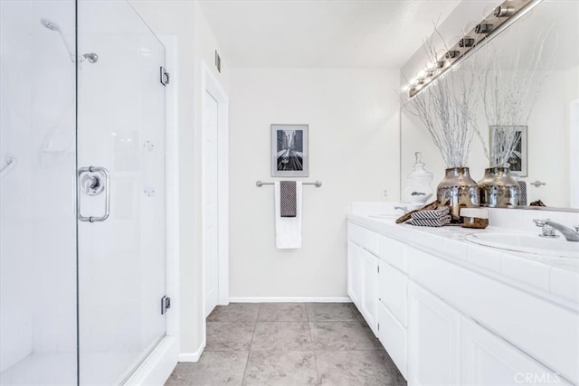 full bath with baseboards, double vanity, a stall shower, a sink, and tile patterned flooring