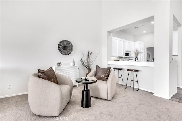 sitting room featuring baseboards, carpet floors, and a towering ceiling