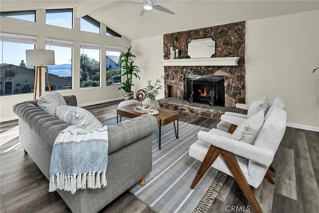 living room with vaulted ceiling with beams, a stone fireplace, baseboards, and wood finished floors