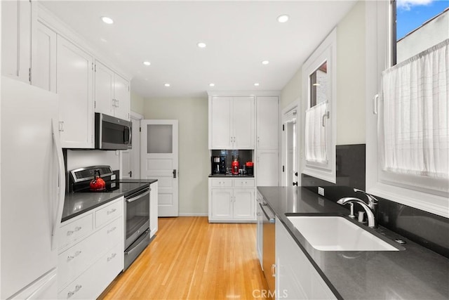 kitchen with stainless steel appliances, a sink, and white cabinets