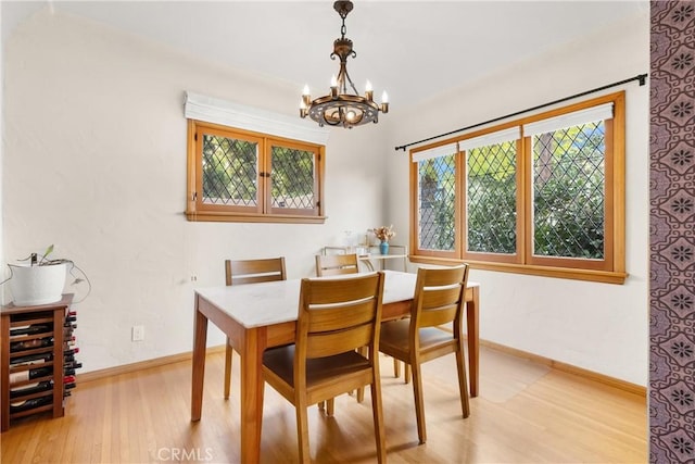 dining area featuring light wood-style floors, baseboards, and an inviting chandelier