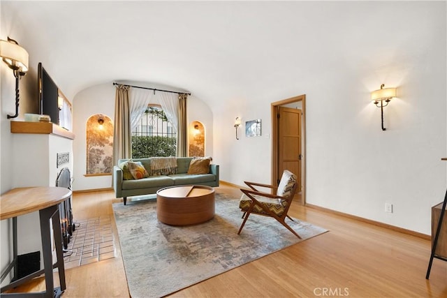 living room featuring vaulted ceiling, light wood-style flooring, and baseboards