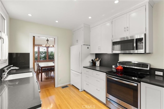 kitchen featuring white cabinets, dark countertops, stainless steel appliances, and a sink