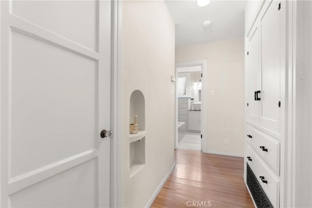 corridor with light wood-type flooring and baseboards