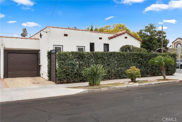 mediterranean / spanish home featuring an attached garage, decorative driveway, and stucco siding