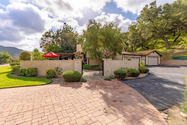 exterior space with a fenced front yard, a mountain view, a detached garage, and a gate