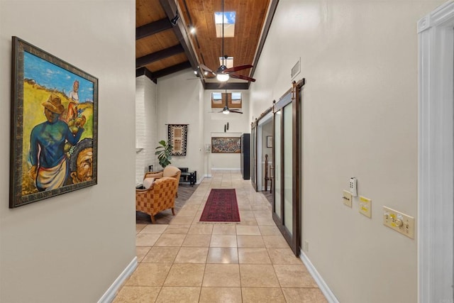 corridor with baseboards, lofted ceiling with skylight, wood ceiling, a barn door, and light tile patterned floors