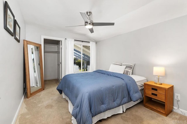 bedroom with a walk in closet, light carpet, vaulted ceiling, ceiling fan, and baseboards