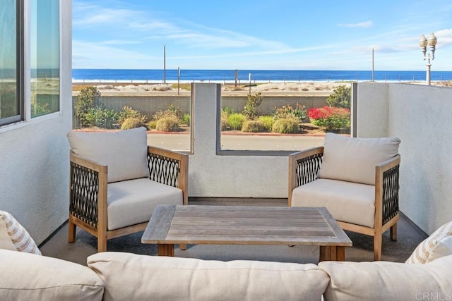 balcony with a view of the beach, a water view, and an outdoor living space