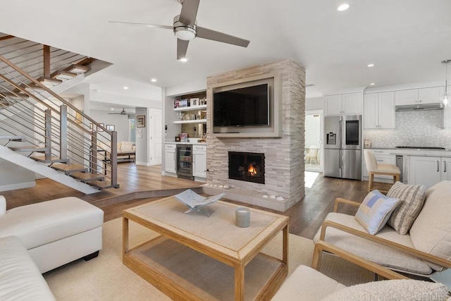 living room with ceiling fan, wine cooler, recessed lighting, wood finished floors, and stairway