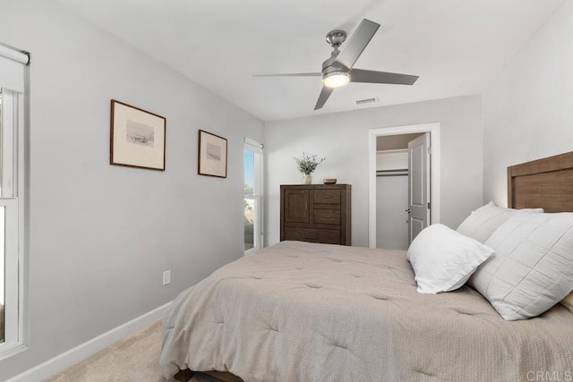 carpeted bedroom with visible vents, a spacious closet, baseboards, and ceiling fan