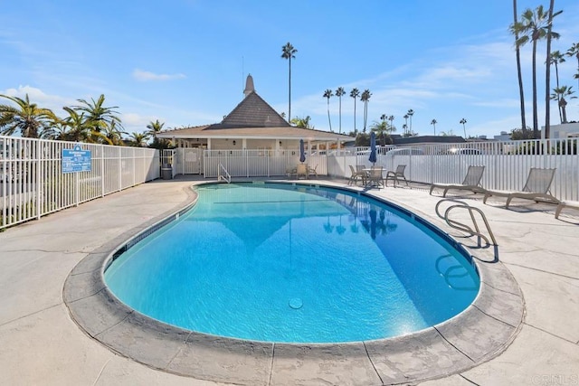 pool with a patio area and fence