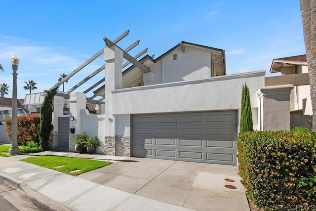 view of front of home with a garage, stone siding, concrete driveway, and stucco siding