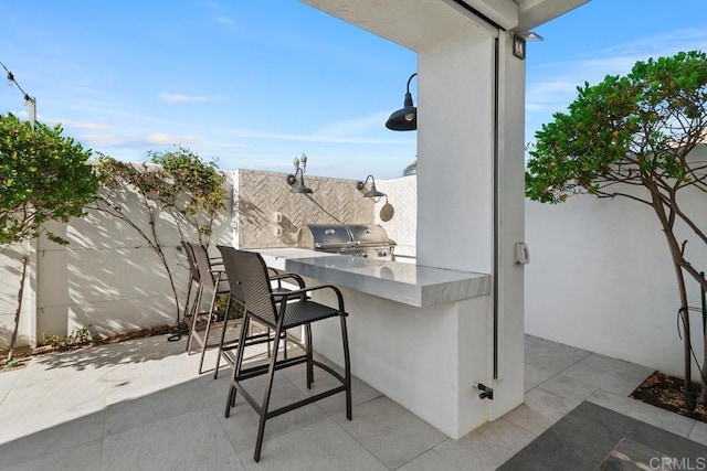 view of patio / terrace with outdoor wet bar, a grill, area for grilling, and fence