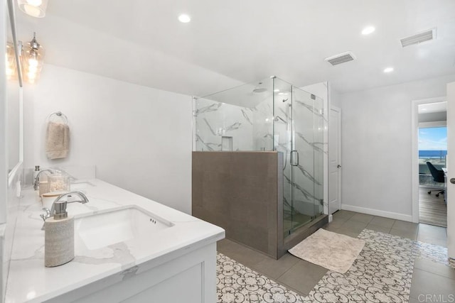 bathroom featuring a marble finish shower, visible vents, a sink, and recessed lighting