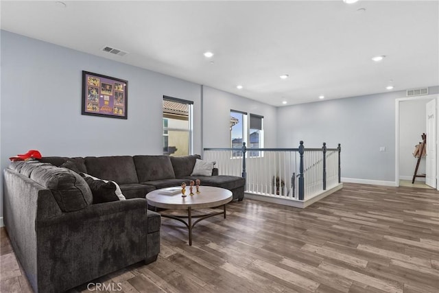 living room with recessed lighting, visible vents, and wood finished floors