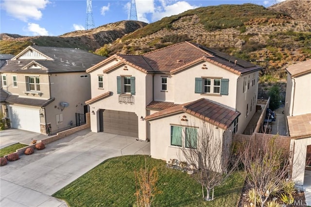 mediterranean / spanish-style home featuring an attached garage, solar panels, a tiled roof, driveway, and stucco siding