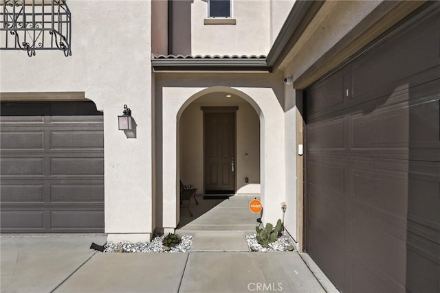 view of exterior entry with a tile roof and stucco siding