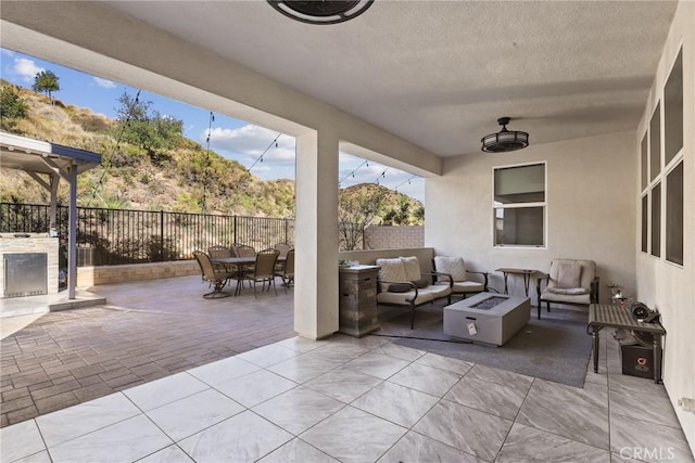 view of patio featuring outdoor dining space, a fenced backyard, and an outdoor living space with a fire pit