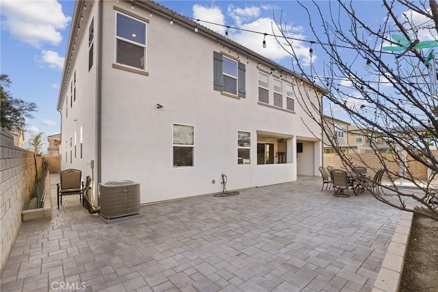 back of property featuring a patio, stucco siding, a fenced backyard, central AC, and outdoor dining space