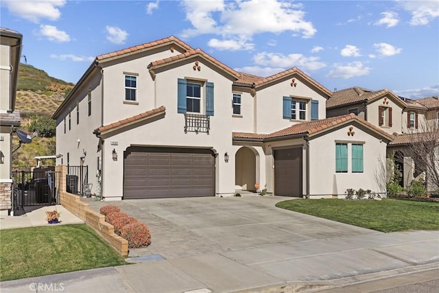 mediterranean / spanish-style house featuring a garage, a front yard, a tiled roof, and stucco siding