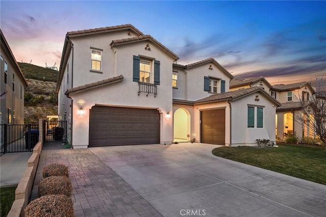 mediterranean / spanish home with a gate, a tile roof, driveway, and an attached garage