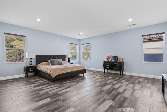 bedroom with wood finished floors, visible vents, and baseboards