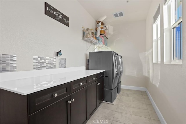 laundry room featuring cabinet space, light tile patterned floors, visible vents, baseboards, and washer and clothes dryer