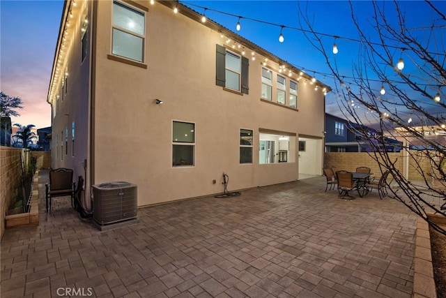 rear view of property featuring central AC unit, a patio, a fenced backyard, outdoor dining area, and stucco siding