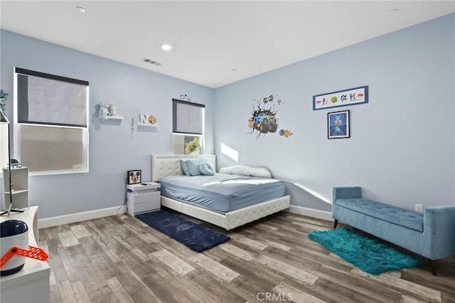 bedroom with baseboards, visible vents, and wood finished floors