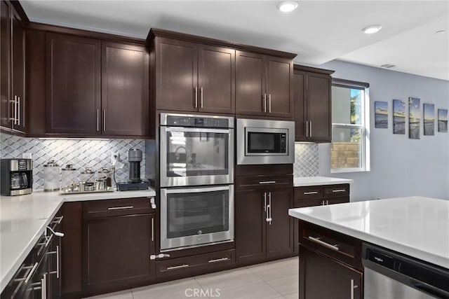 kitchen featuring dark brown cabinetry, tasteful backsplash, appliances with stainless steel finishes, light countertops, and recessed lighting