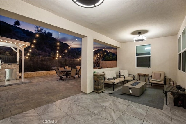 view of patio / terrace with fence private yard, an outdoor living space with a fire pit, a ceiling fan, and outdoor dining space