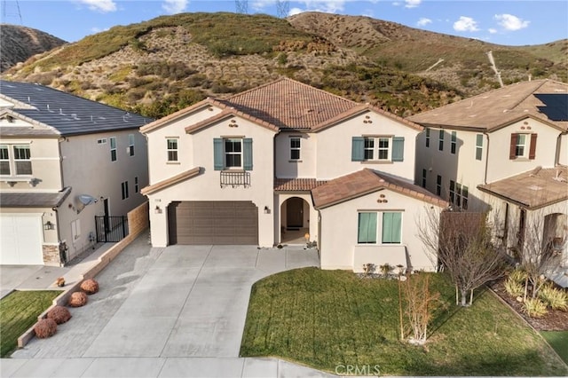 mediterranean / spanish-style home featuring a garage, stucco siding, a tiled roof, a mountain view, and driveway