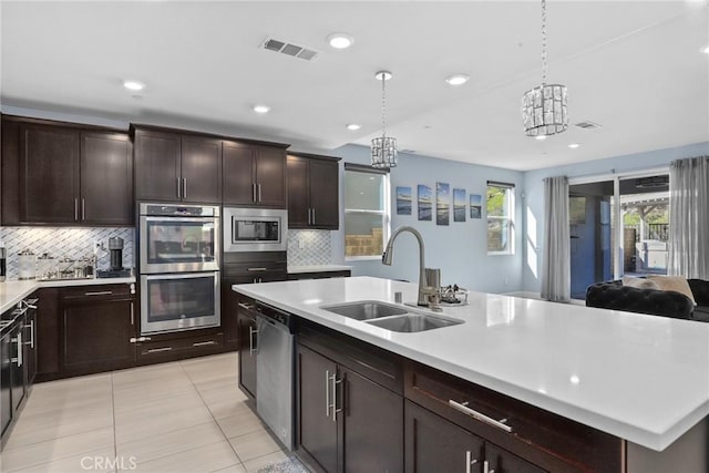 kitchen featuring light tile patterned floors, stainless steel appliances, a sink, visible vents, and light countertops