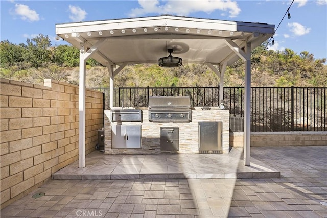 view of patio / terrace featuring a grill, an outdoor kitchen, a fenced backyard, and a gazebo