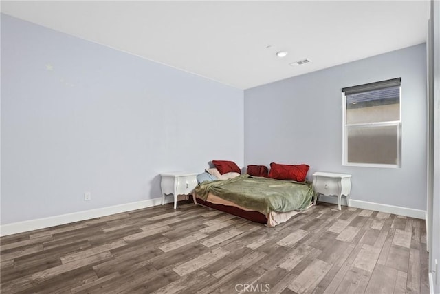 bedroom featuring visible vents, baseboards, and wood finished floors