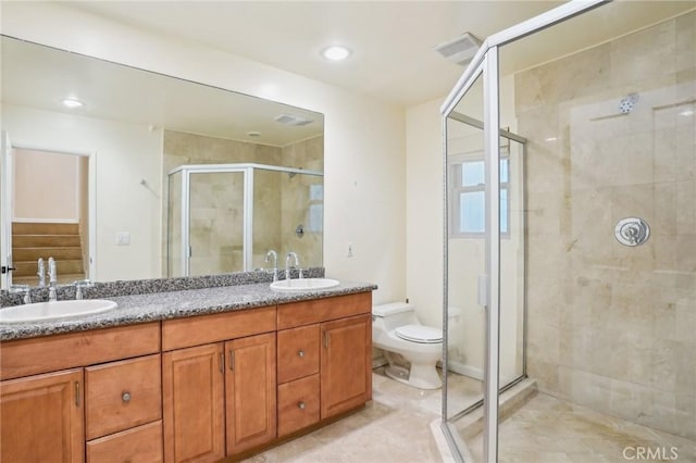 bathroom featuring toilet, a sink, double vanity, and a stall shower