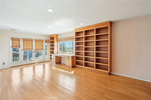 unfurnished living room with recessed lighting, baseboards, light wood-style floors, french doors, and built in study area