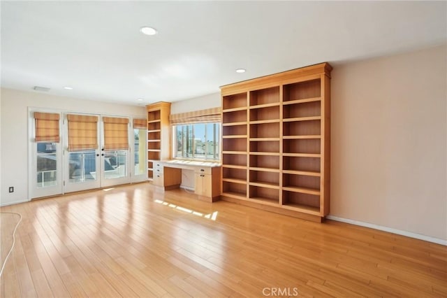 unfurnished living room featuring light wood-style flooring, visible vents, baseboards, built in desk, and recessed lighting