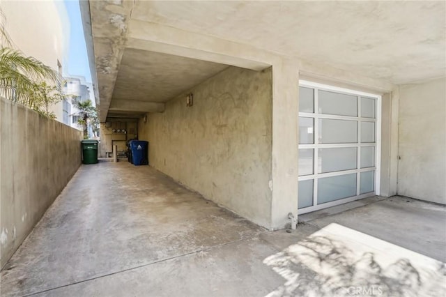 doorway to property with stucco siding, fence, and a garage