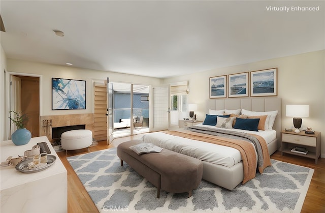 bedroom with access to exterior, wood finished floors, and a fireplace