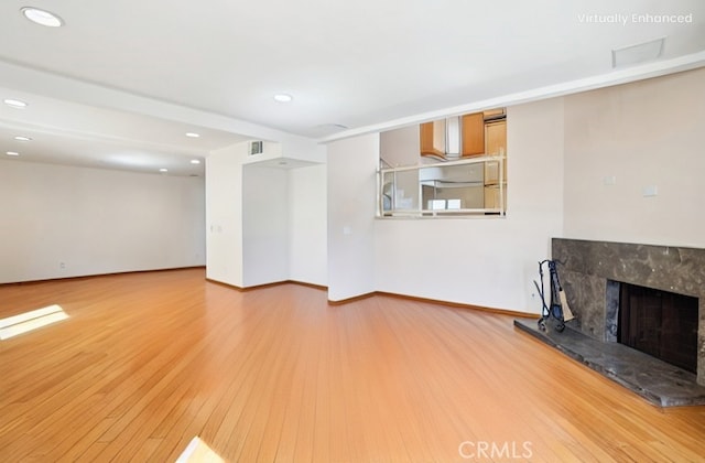 unfurnished living room featuring a premium fireplace, recessed lighting, wood finished floors, and baseboards