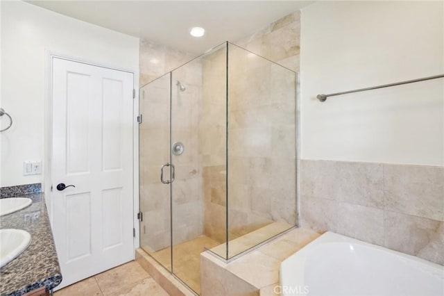 full bath featuring tile patterned floors, a sink, double vanity, a stall shower, and a garden tub