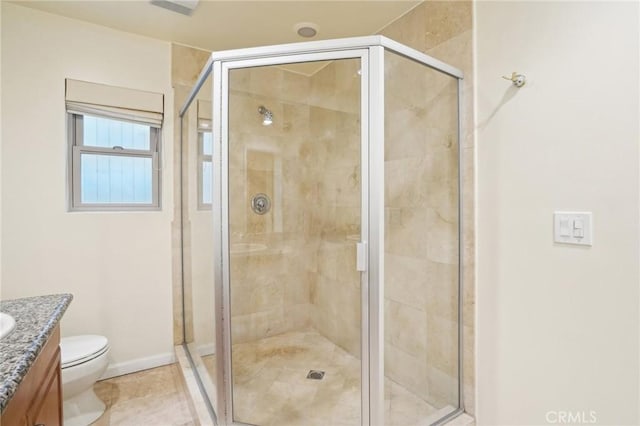 bathroom featuring toilet, a shower stall, vanity, and baseboards