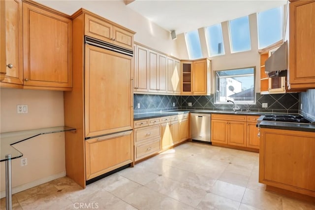 kitchen featuring under cabinet range hood, backsplash, dark countertops, stainless steel dishwasher, and paneled built in refrigerator