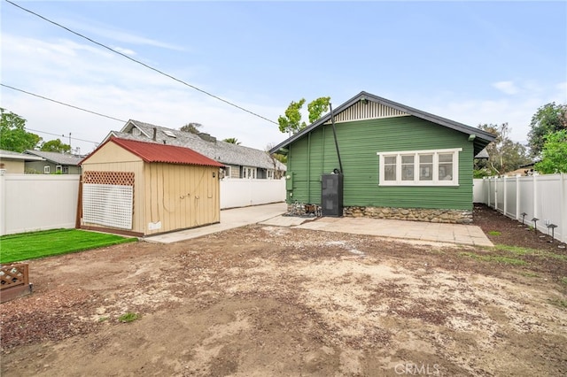 rear view of property with a fenced backyard, an outdoor structure, and a storage unit