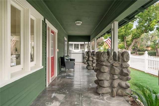 view of patio featuring covered porch and fence